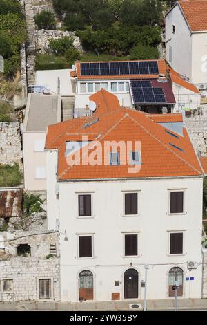 Vue en angle élevé de l'immeuble d'appartements blancs et de la maison avec panneaux solaires sur le toit traditionnel en tuiles d'argile en terre cuite sur le mont SRD à la fin de l'été, Dubro Banque D'Images