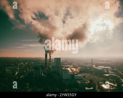 installation industrielle avec cheminées émettant de la fumée. Le paysage industriel combiné avec le soleil couchant crée un contraste entre la nature et l'humain A. Banque D'Images