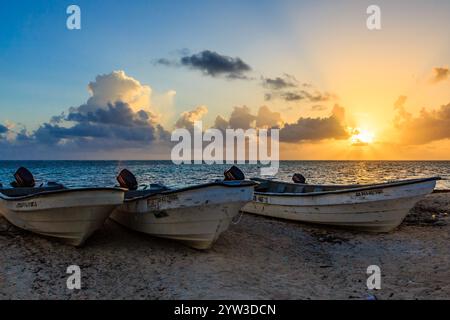 Trois bateaux sont assis sur la plage, dont l'un est étiqueté 'SP-1'. Le ciel est bleu et le soleil se couche, créant une atmosphère paisible et sereine Banque D'Images