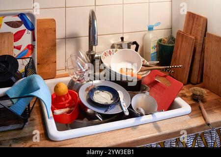 Un évier de cuisine encombré rempli de vaisselle sale, y compris des casseroles, des poêles, des ustensiles et de la verrerie, Allemagne Banque D'Images