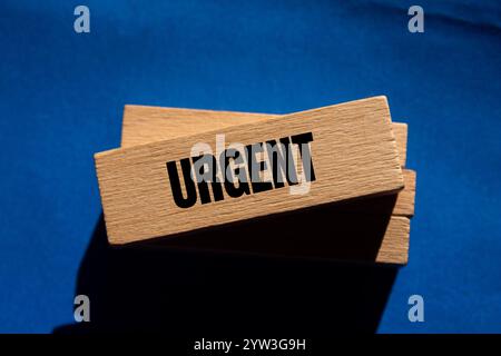 Message urgent écrit sur des blocs de bois avec fond bleu. Symbole conceptuel de mot urgent. Copier l'espace. Banque D'Images
