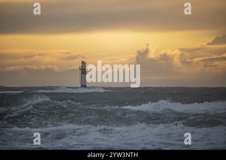 Un phare se dresse dans la tempête. Mer sauvage dans la soirée. Coucher de soleil sur une côte avec de nombreux rochers dans la mer du Nord. Paysage marin en Suède, Scandinavie Banque D'Images