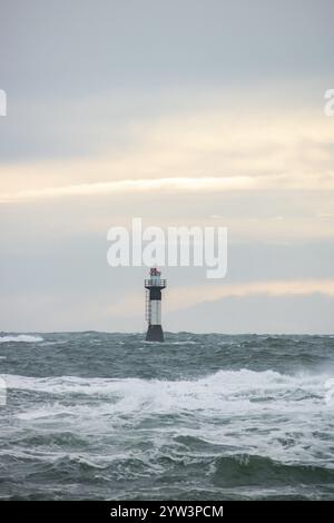 Un phare se dresse dans la tempête. Mer sauvage dans la soirée. Coucher de soleil sur une côte avec de nombreux rochers dans la mer du Nord. Paysage marin en Suède, Scandinavie Banque D'Images