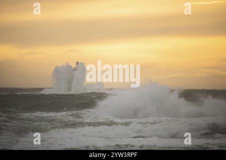 Un phare se dresse dans la tempête. Mer sauvage dans la soirée. Coucher de soleil sur une côte avec de nombreux rochers dans la mer du Nord. Paysage marin en Suède, Scandinavie Banque D'Images