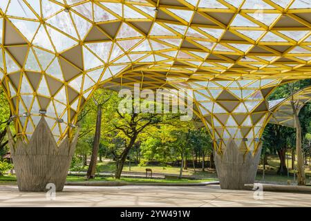 Jardin botanique de Perdana, Kuala Lumpur, Malaisie avec une structure architecturale moderne avec un toit géométrique jaune et un grand espace ouvert entouré par Banque D'Images