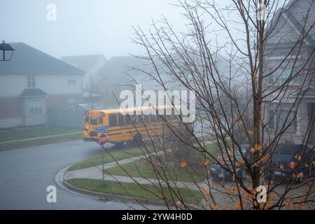 Un autobus scolaire dans le brouillard matinal recueille les écoliers dans les rues de la ville Banque D'Images