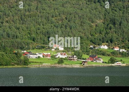 Un village pittoresque dans l'ouest de la Norvège niché par un fjord, entouré de forêts verdoyantes et de collines, avec des maisons traditionnelles en bois et une sere Banque D'Images