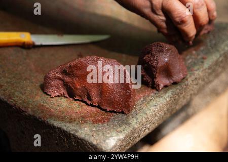 Chocolat biologique de la région de Oaxaca au Mexique produit de manière traditionnelle sur un métate, un outil en pierre ancien pour le broyage des produits. Banque D'Images