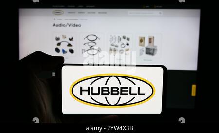 Dans cette illustration photo, une personne tient un téléphone portable avec le logo de la société d'électronique américaine Hubbell Incorporated devant la page Web de l'entreprise. Banque D'Images