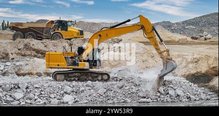 Une excavatrice et un dumper travaillant sur un remblai de pierre Banque D'Images