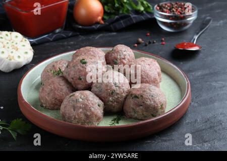 Beaucoup de boulettes de viande fraîches crues sur table noire Banque D'Images