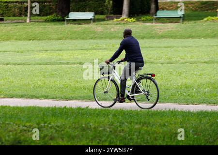 Journée parfaite pour faire du vélo. Vue arrière d'un homme à vélo le long de la route dans le parc de la ville de Mantoue Banque D'Images