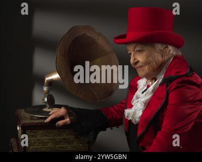 mélodies de mémoire... Une femme âgée à côté d'un vieux téléphone... nous nous souvenons, nous nous souvenons. Banque D'Images