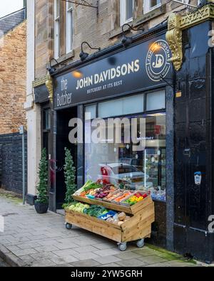 9 décembre 2024. High Street, Elgin, Moray, Écosse. Il s'agit d'une boucherie, la boucherie de John Davidson avec son chariot de légumes sur les pavés Banque D'Images