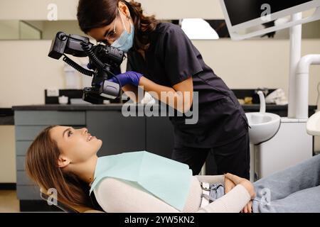 Femme dentiste photographiant avec un appareil photo professionnel le résultat de son travail en clinique. Banque D'Images