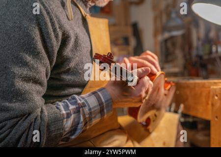 Luthier assemblant un rouleau de violon dans son atelier, en utilisant des techniques et des outils traditionnels Banque D'Images