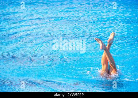 Femme nageuse artistique effectuant des mouvements de jambes chorégraphiés dans la piscine Banque D'Images