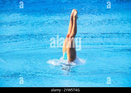 Femme nageuse artistique effectuant des mouvements de jambes chorégraphiés dans la piscine Banque D'Images