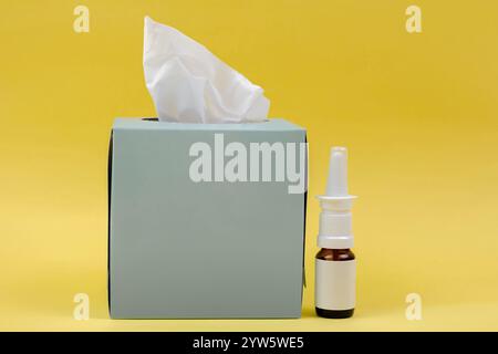 Sur l'image, il y a une boîte de tissus et un spray nasal sur un fond jaune. Les choses dont vous avez besoin au cas où vous auriez un rhume. Banque D'Images