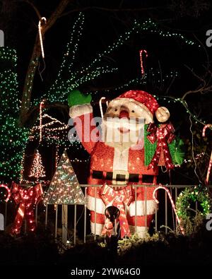 Une décoration festive du Père Noël brille brillamment parmi les cannes de bonbons, les couronnes et les lumières des fêtes, répandant la joie de Noël lors d'une nuit sombre d'hiver Banque D'Images