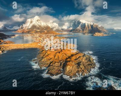 Vue aérienne des montagnes enneigées, mer bleue, village au lever du soleil Banque D'Images