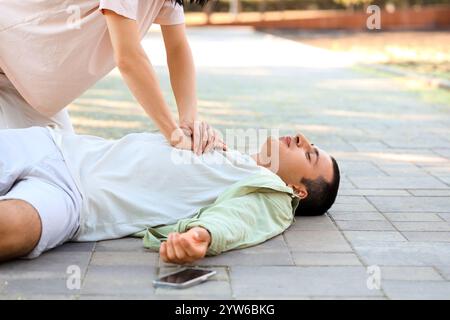 Jeune femme faisant la RCP sur un homme inconscient ayant une crise cardiaque dans la rue Banque D'Images