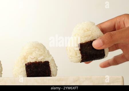 Main femelle prenant Onigiri riz japonais avec forme de triangle et Nori Banque D'Images