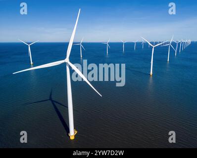 Un groupe de moulins à vent flotte gracieusement dans la région néerlandaise de Flevoland pendant la saison vibrante du printemps. drone vue aérienne de rangée de turbines éoliennes énergie verte dans l'océan bleu Banque D'Images