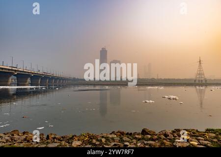 Ville brumeuse avec pont routier et effluents industriels et domestiques mousse toxique dans la rivière contaminée au lever du soleil spectaculaire image est prise à la rivière yamuna Banque D'Images