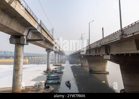 Pont routier moderne enjambant la rivière contaminée avec la mousse toxique et le bateau de travailleurs à brumeux matin vidéo est prise à yamuna rivière okhla barrage delhi Banque D'Images