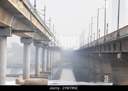 Pont routier moderne enjambant la rivière contaminée avec la mousse toxique et le bateau de travailleurs à brumeux matin vidéo est prise à yamuna rivière okhla barrage delhi Banque D'Images