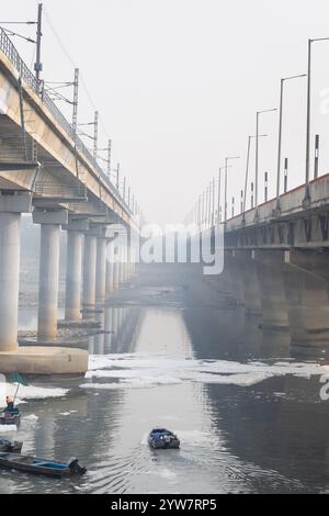 Pont routier moderne enjambant la rivière contaminée avec la mousse toxique et le bateau de travailleurs à brumeux matin vidéo est prise à yamuna rivière okhla barrage delhi Banque D'Images