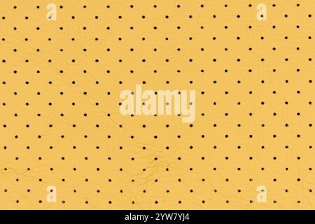 Cuir artificiel abstrait de couleur jaune avec petits points et motifs de trous pour le fond. Gros plan vue de dessus de la surface respirante couleur sable Banque D'Images