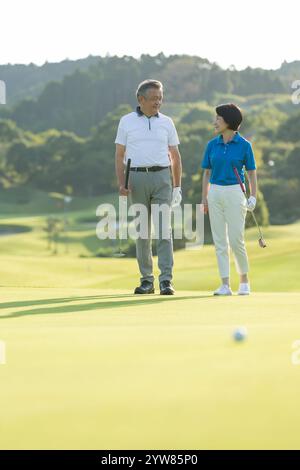 Senior couple walking on golf course Banque D'Images