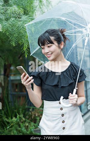 Femme marchant sous la pluie, smartphone Banque D'Images