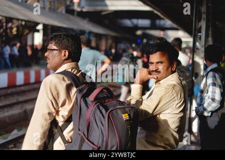 Voyageurs de chemin de fer masculins attendant un train de banlieue de la Central Line, debout sur un quai à la gare de Dadar à Mumbai, en Inde Banque D'Images