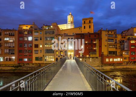 Vue nocturne de maisons colorées sur la rive de la rivière à Gérone avec un pont piétonnier menant à la partie historique de la ville, Espagne Banque D'Images