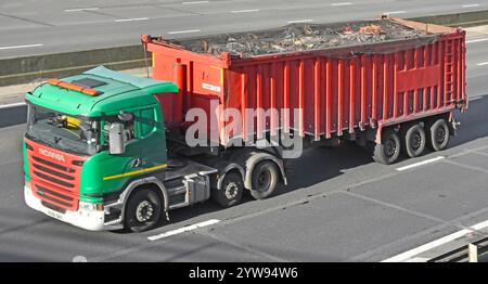 Vert Scania hgv Unmaked Haulage entrepreneur remorquant rouge toit ouvert semi-remorque filet couvercle charge déchets généraux conduite autoroute M25 route Angleterre royaume-uni Banque D'Images