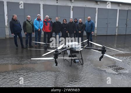 Litovel, République tchèque. 10 décembre 2024. Drone DJI Agras T50, qui sera utilisé pour l’application efficace de pulvérisations de moustiques dans les villages situés à proximité de la zone paysagère protégée de Litovelske Pomoravi, Litovel, région d’Olomouc, 10 décembre 2024. Le drone est équipé d’une technologie de pointe et permet l’application d’agents liquides ou d’arrosage en agriculture. Sur la photo les maires des villages touchés par la calamité annuelle des moustiques dans une photo de groupe avec le nouveau drone. Crédit : Ludek Perina/CTK photo/Alamy Live News Banque D'Images