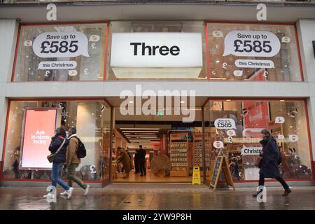 Londres, Royaume-Uni. 5 décembre 2024. Les gens passent devant un magasin de téléphonie mobile de trois à Oxford Street que la fusion de trois avec Vodafone est approuvée. Crédit : Vuk Valcic/Alamy Banque D'Images