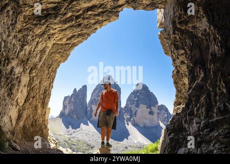 Randonneur profitant de la vue panoramique de Tre cime di lavaredo, un symbole des dolomites, de l'intérieur d'une montagne Tre Cime Cave lors d'une randonnée estivale Banque D'Images