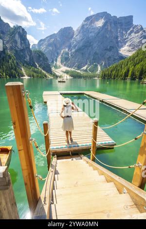 Femme debout sur la jetée en bois, admirant le paysage magnifique du lac braies avec des eaux émeraude et des montagnes majestueuses dans les dolomites, italie Banque D'Images