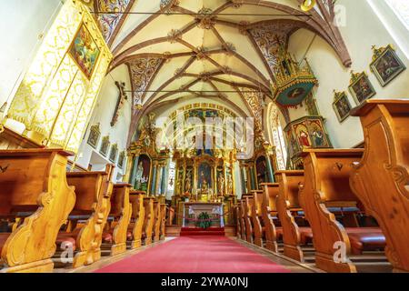 Intérieur de l'église de St. Magdalena in val di funes, montrant des fresques, des bancs et du tapis rouge, dans les dolomites, italie Banque D'Images