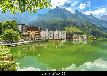 Scène estivale tranquille du village d'alleghe reflétant sur les eaux émeraude du lac alleghe, niché au milieu des superbes montagnes des dolomites en italie Banque D'Images