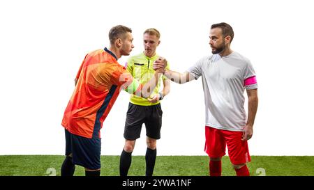Deux hommes sérieux, joueurs de football de l'équipe opposée, debout à côté de l'arbitre et serrant la main isolés sur fond blanc Banque D'Images