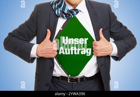 Homme d'affaires en costume montrant le slogan Unser Auftrag (allemand pour : «notre Mission») sous sa chemise comme un concept d'entreprise Banque D'Images