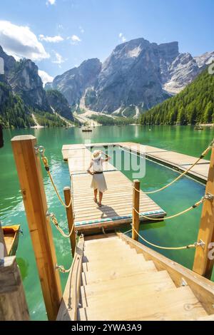 Touriste bénéficiant d'une vue imprenable sur le lac braies dans les dolomites italiennes, debout sur une jetée en bois aux eaux émeraude et aux montagnes majestueuses Banque D'Images