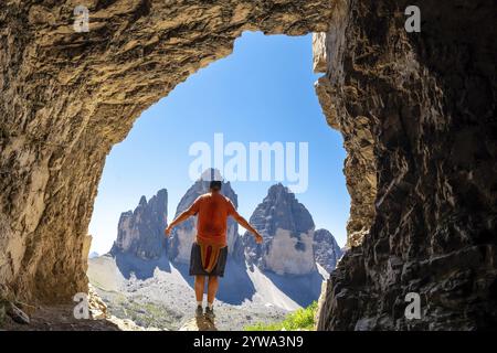 Randonneur profitant de la vue imprenable sur la Tre cime di lavaredo depuis l'intérieur d'une grotte de Tre Cime dans les dolomites italiennes Banque D'Images