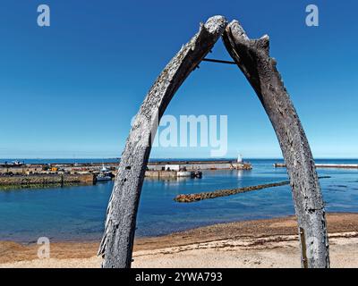 Royaume-Uni, Northumberland, Seahouses, Whale Jaw Bones surplombant l'entrée du port de North Sunderland et le phare. Banque D'Images