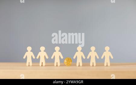 Figurines miniatures en bois de personnes debout au bureau dans la rangée avec bitcoin au milieu Banque D'Images